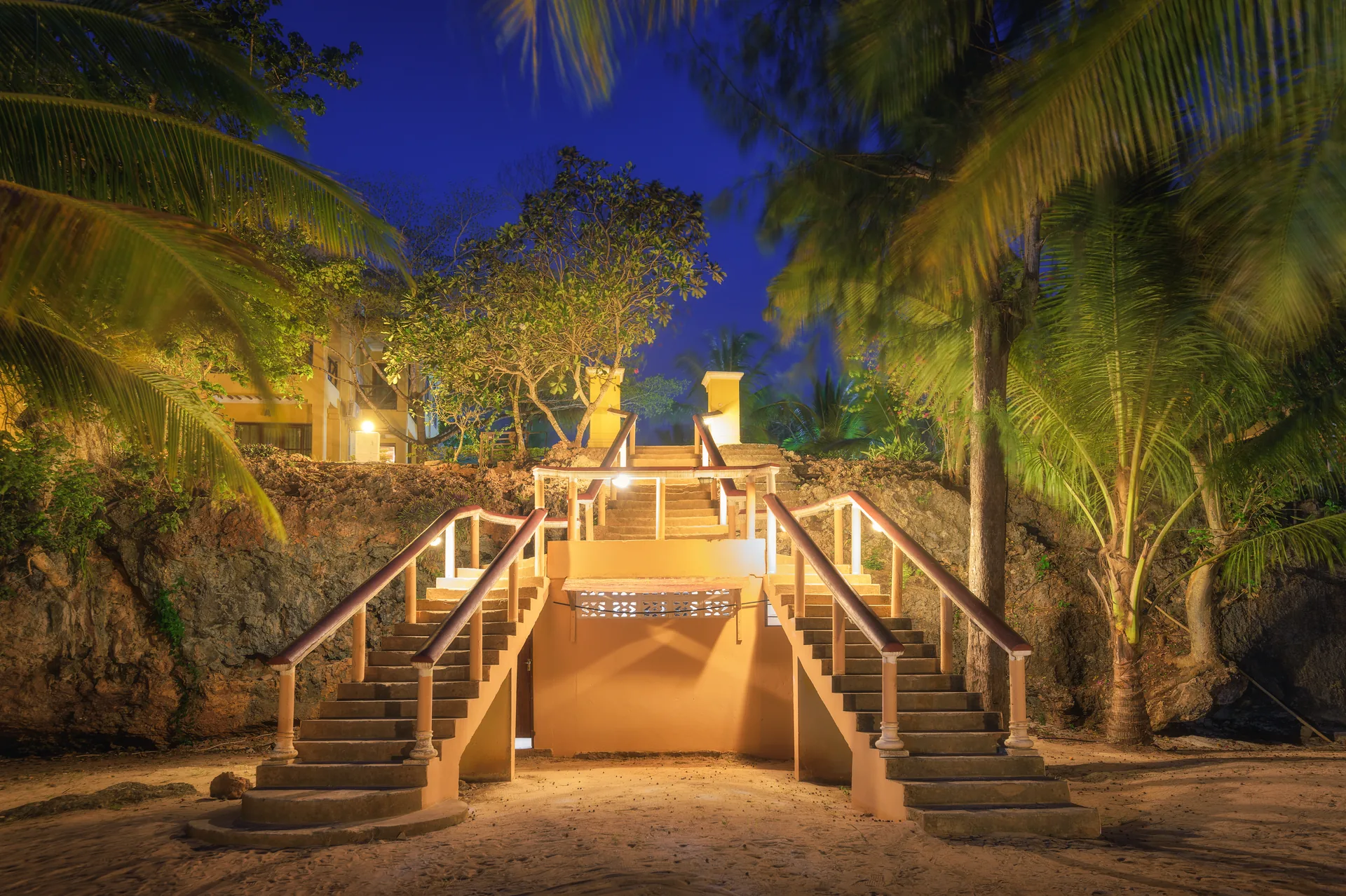 Escadaria iluminada em ambiente tropical ao anoitecer